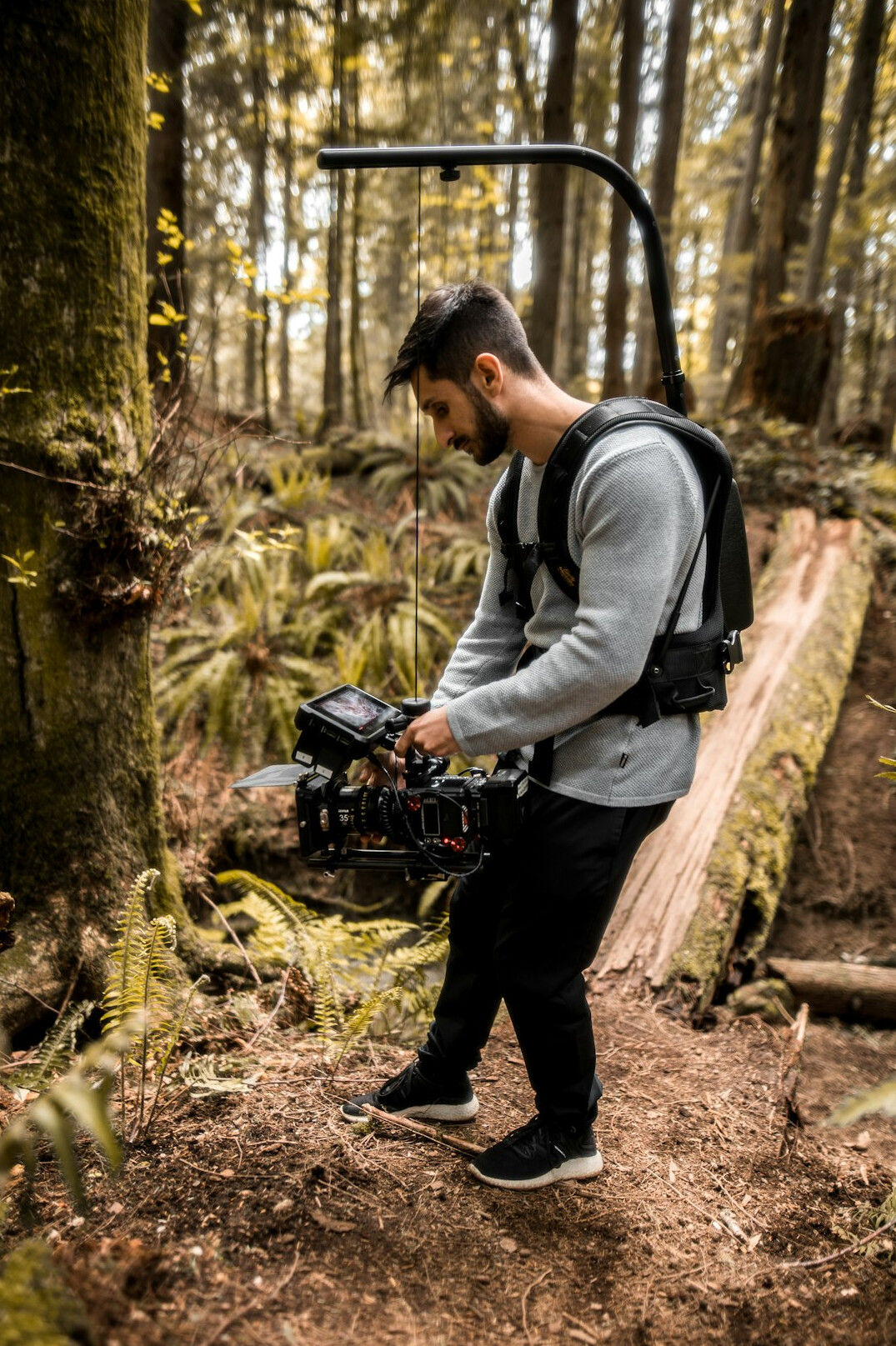 British camera operator with curly hair holding a professional camera to their eye